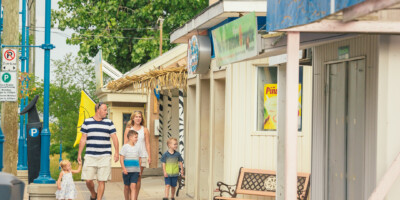 LOCATION: GRAND BEND, ON Family walking down the street in front of store fronts in Grand Bend