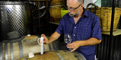 Man drawing wine from a cask at Alton Farms Winery