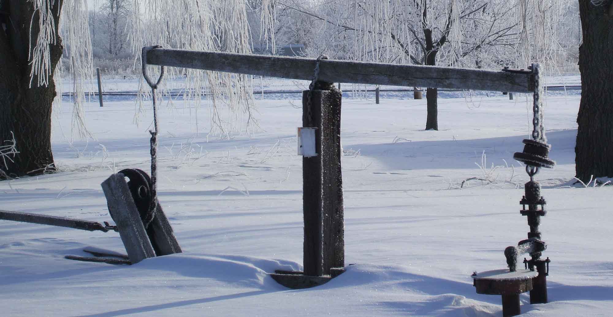 historical pump jack covered in snow