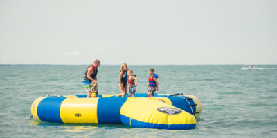 LOCATION: GRAND BEND, ON Family playing on a large water toy in Grand Bend