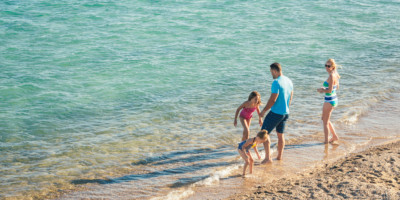 LOCATION: SARNIA, ON Family playing on the beach at the waters edge in Sarnia