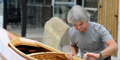 Man checking the rim of a hand made wooden kayak