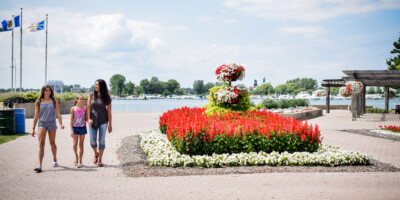 Mother and two daughters walking past flowers in Centennial Park, Sarnia