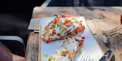 close up of gourmet flat pizza being eaten outside